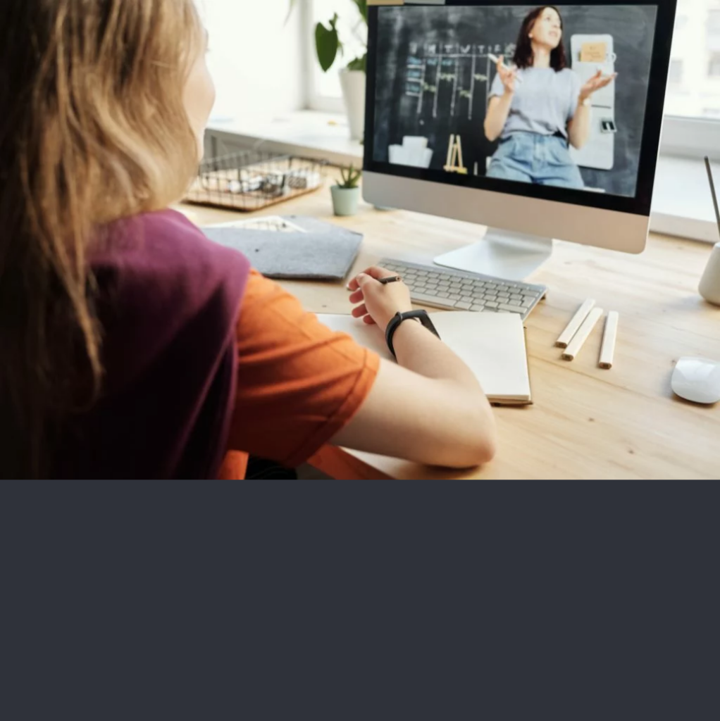 Photo of a woman sitting on a table infront of a computer