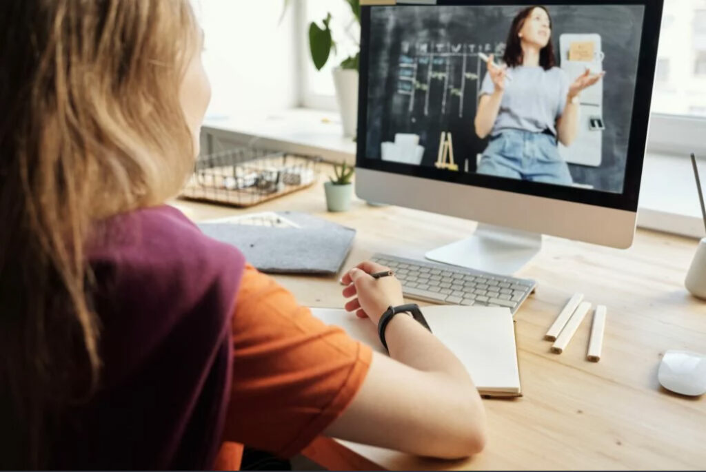 Photo of a woman sitting on a table infront of a computer