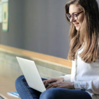 Frau sitzt mit Notebook vor einer Tafel