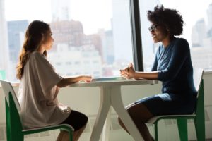 zwei Frauen sitzen am Tisch und reden