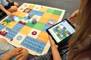 Bild, auf dem Kinder mit Spieldecke und Tablet lernen