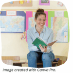 A teacher sitting on a desk, looking up from a book, laughing and looking happy.