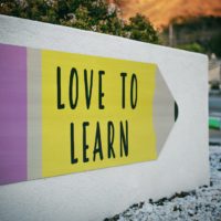 Foto von einem Plakat im Stiftform auf eine Mauer mit der Beschriftung "Love to learn"